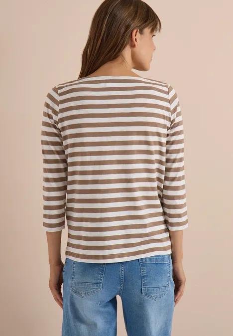 T-shirt basique à col bateau et rayures natural taupe Frau von hinten in gestreiftem Dreiviertelarm-Shirt und blauen Jeans vor neutralem Hintergrund.