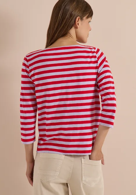 Rückansicht einer Frau mit rot-weiß gestreiftem 3/4-Armshirt und hellen Hosen.