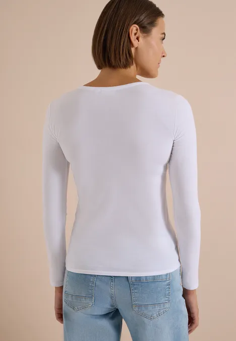 Basic Shirt mit Rundhals im 2er-Pack urban dark blue/white Frau von hinten in weißem Langarmshirt und hellblauen Jeans vor einfarbigem, beigem Hintergrund.