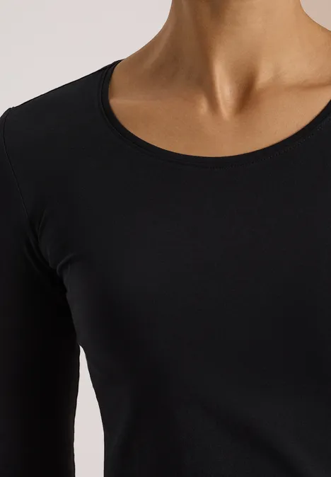 Nahaufnahme eines Oberkörpers in einem schwarzen Langarmshirt vor hellem Hintergrund.
