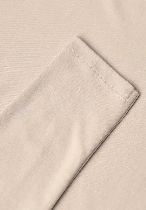 Longsleeve met V-hals cashmere beige Nahe Aufnahme eines beigen Baumwollstücks mit sichtbarer Saumnaht am Rand.