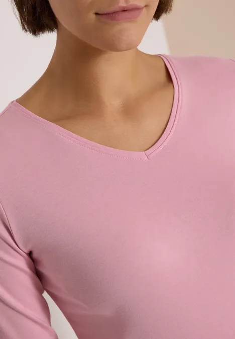 Nahaufnahme einer Person im rosafarbenen V-Ausschnitt-Shirt.