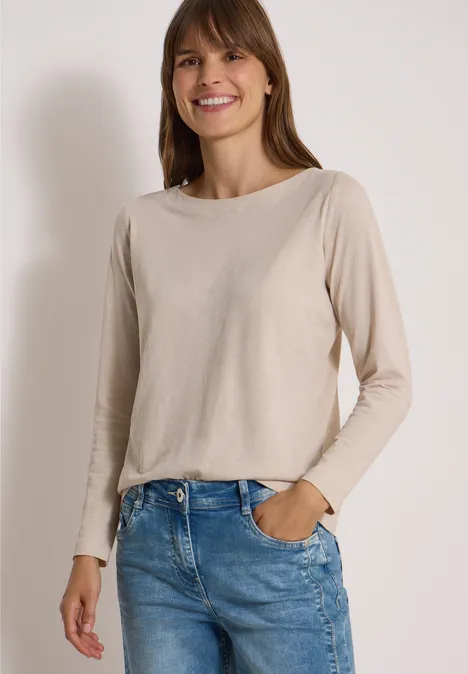 Langarm Shirt mit U-Boot-Ausschnitt cashmere beige Lächelnde Frau in beige langärmligem Shirt und blauen Jeans, steht mit einer Hand in der Tasche.