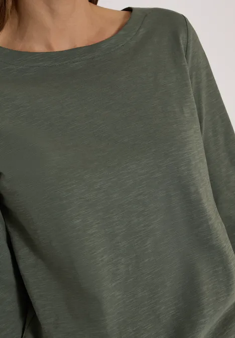 Langarm Shirt mit U-Boot-Ausschnitt dried olive green Frau trägt ein schlichtes olivgrünes Langarmshirt aus leicht strukturierter Baumwolle.