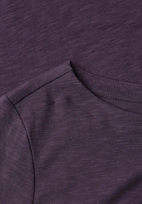 Nahaufnahme eines lila T-Shirts mit Rundhalsausschnitt und Schulterpartie.