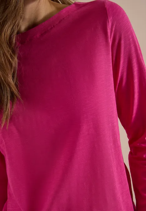 Langarm Shirt mit U-Boot-Ausschnitt pink flash Eine Person trägt ein fuchsiafarbenes, langärmliges Oberteil, Nahaufnahme.