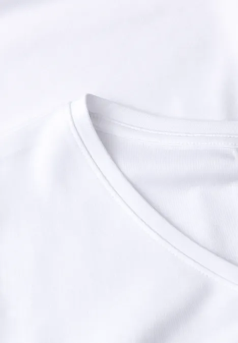 Gros plan d’un t-shirt blanc à col rond sur fond clair.