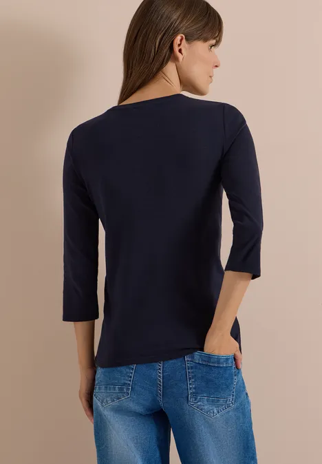 3/4-Arm Shirt in Unifarbe mit V-Neck urban dark blue Rückenansicht einer Frau mit dunkelblauem Dreiviertelarmshirt und blauen Jeans vor beigem Hintergrund.