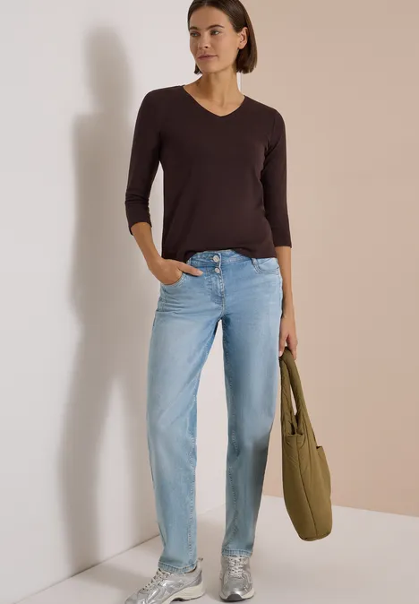 3/4-Arm Shirt in Unifarbe mit V-Neck truffle brown Frau trägt dunkelbraunen V-Ausschnitt-Pullover, helle Jeans, silberne Sneakers und eine olivgrüne Schultertasche.