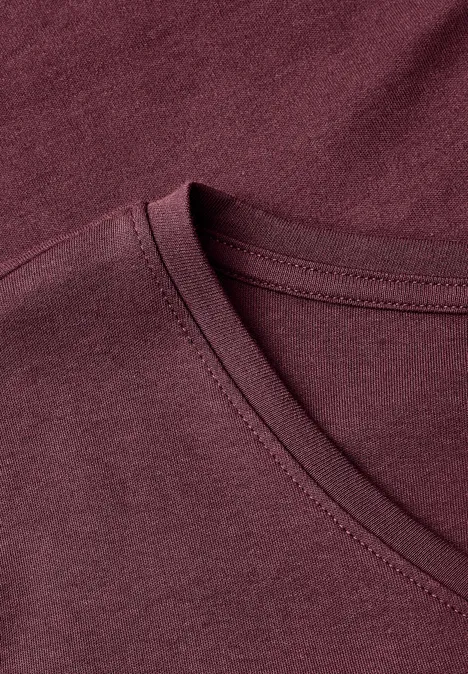 Gros plan sur un T-shirt col V de couleur bordeaux en tissu doux.
