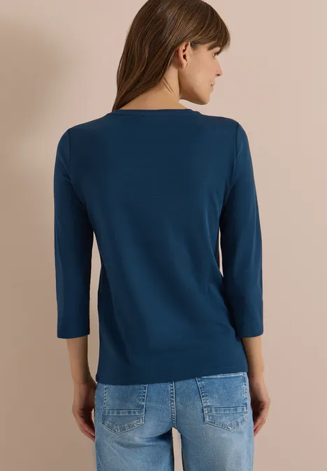 3/4-Arm Shirt in Unifarbe mit V-Neck moonlight blue Rückenansicht einer Frau im dunkelblauen 3/4-Arm-Shirt und Jeans vor hellem Hintergrund.
