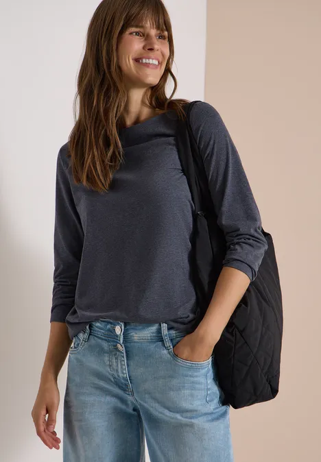 Langarm Shirt mit U-Boot-Ausschnitt urban dark blue melange Junge Frau in lässigem grauen Langarmshirt, Jeans und Schultertasche, lächelnd an einer hellen Wand.