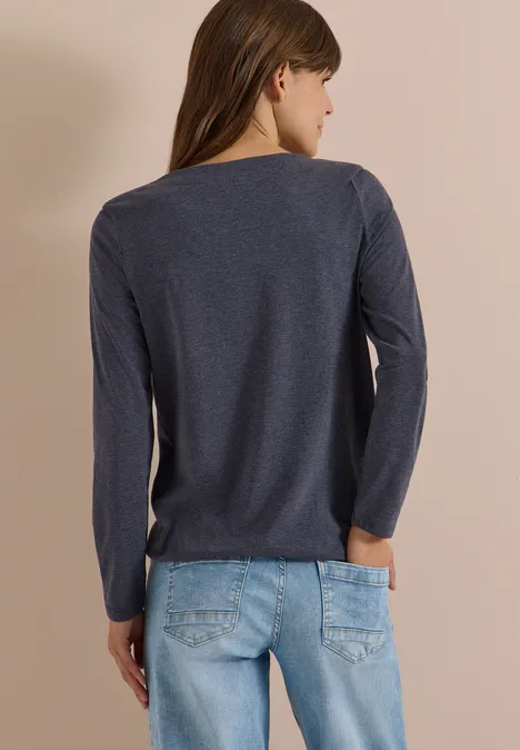 Langarm Shirt mit U-Boot-Ausschnitt urban dark blue melange Frau von hinten in dunkelblauem Langarmshirt und hellblauen Jeans vor beigefarbenem Hintergrund.