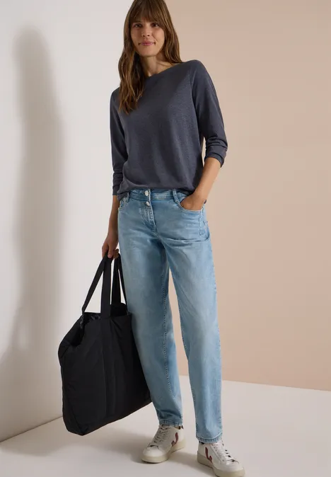 Langarm Shirt mit U-Boot-Ausschnitt urban dark blue melange Frau in dunkelblauem Pullover, hellen Jeans und Sneakern, die eine große schwarze Tasche trägt.