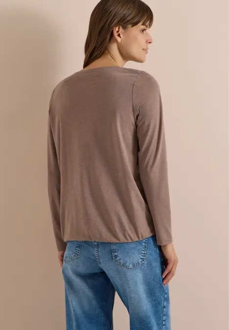 Langarm Shirt mit U-Boot-Ausschnitt urban taupe melange Frau von hinten in braunem Langarmshirt und blauen Jeans vor beigem Hintergrund.