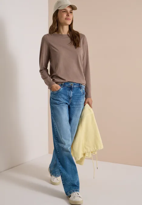 Langarm Shirt mit U-Boot-Ausschnitt urban taupe melange Junge Frau trägt Cap, braunes Langarmshirt, weite blaue Jeans, Sneakers und hält gelbe Jacke.