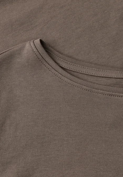 Nahaufnahme gestapelter, beigebrauner Baumwoll-T-Shirts mit sichtbaren Nähten am Rundhalsausschnitt.