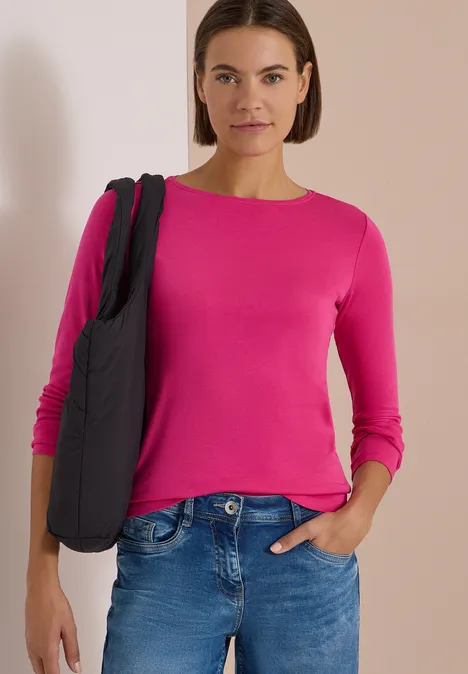 Langarm Shirt mit U-Boot-Ausschnitt pink flash Frau mit pinkem Langarmshirt und Jeans trägt eine schwarze Tasche und steht vor hellem Hintergrund.