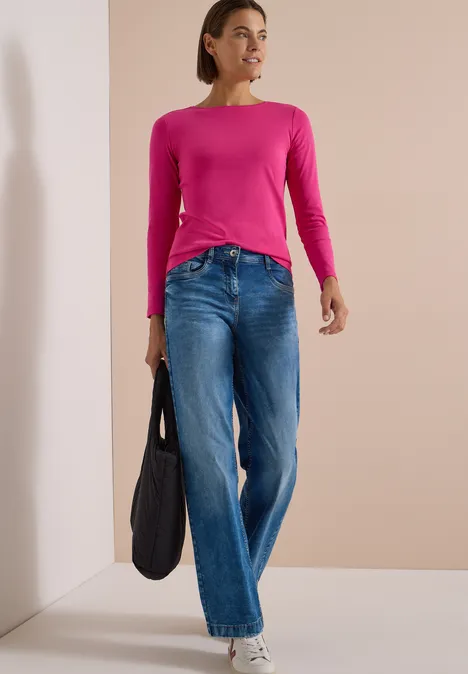 Langarm Shirt mit U-Boot-Ausschnitt pink flash Frau in pinkem Langarmshirt und Jeans mit schwarzer Tasche in hellem Raum.