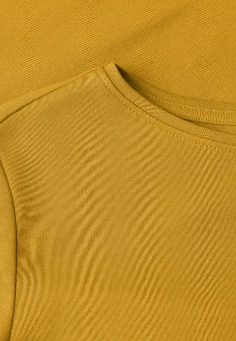 Nahaufnahme eines senfgelben T-Shirts mit Rundhalsausschnitt und Schulternaht