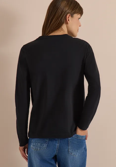Rückansicht eines Modells, das ein schlichtes schwarzes Langarmshirt und blaue Jeans trägt.