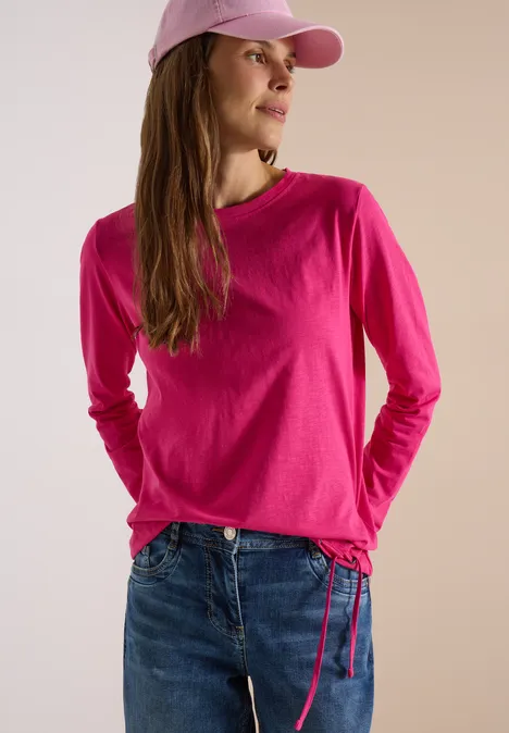 Langarm Shirt mit Rundhals und Tunnelzug pink flash Frau trägt pinkes Langarmshirt mit Tunnelzug, Jeans und pinkes Cap.