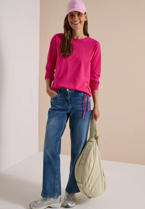 Langarm Shirt mit Rundhals und Tunnelzug pink flash Frau in pinkem Langarmshirt, blauen Jeans, rosa Cap und großer Schultertasche
