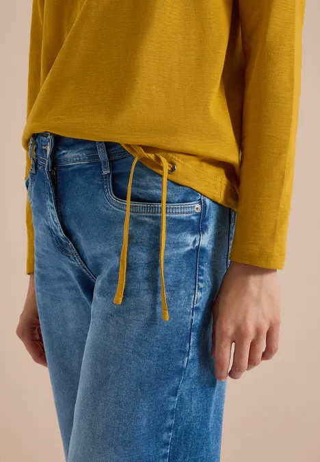 Vue partielle d’une personne portant un haut jaune et un jean bleu