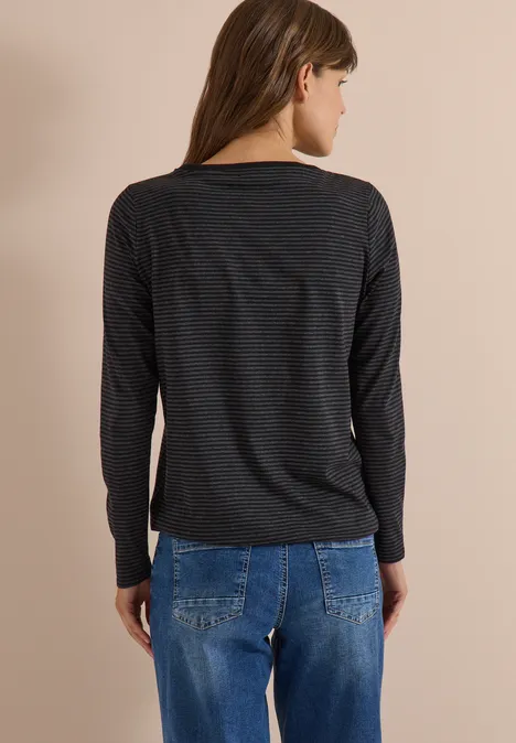 Rückansicht einer Frau in einem dunklen Langarmshirt und blauen Jeans.