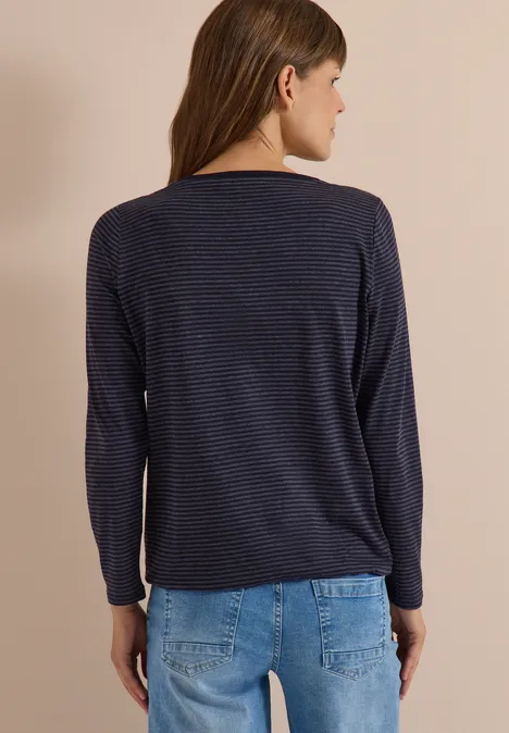 Frau von hinten in dunkelblau geringeltem Langarmshirt und hellblauen Jeans.