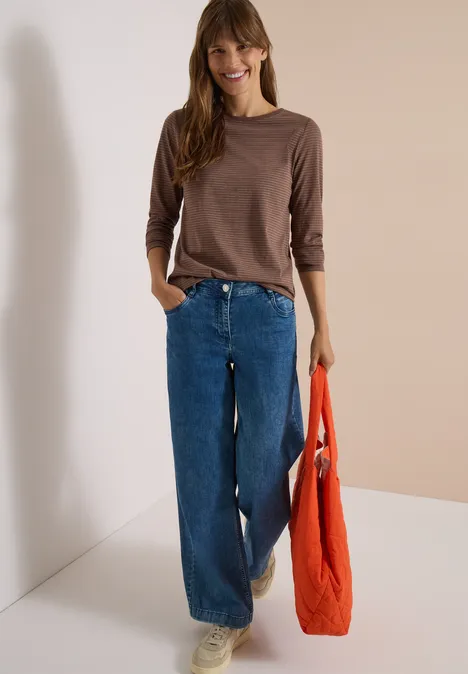Langarm Shirt mit Boat Neck und Streifen urban taupe Frau in braunem Langarmshirt, weiten Jeans und weißen Sneakers hält eine orangefarbene Tasche und lächelt.