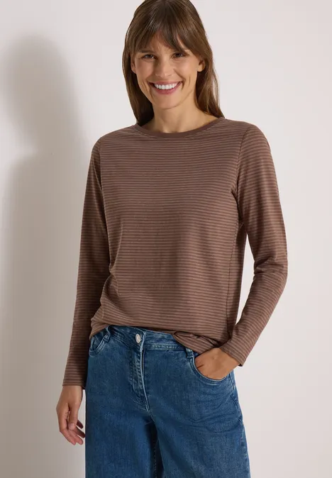Langarm Shirt mit Boat Neck und Streifen urban taupe Frau in braunem gestreiftem Langarm-Shirt und blauen Jeans lächelnd vor neutralem Hintergrund.