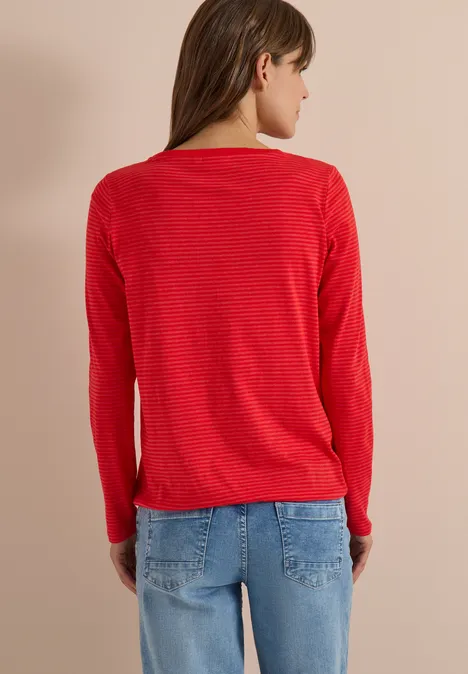 Eine Person von hinten in rotem Pullover und blauer Jeans
