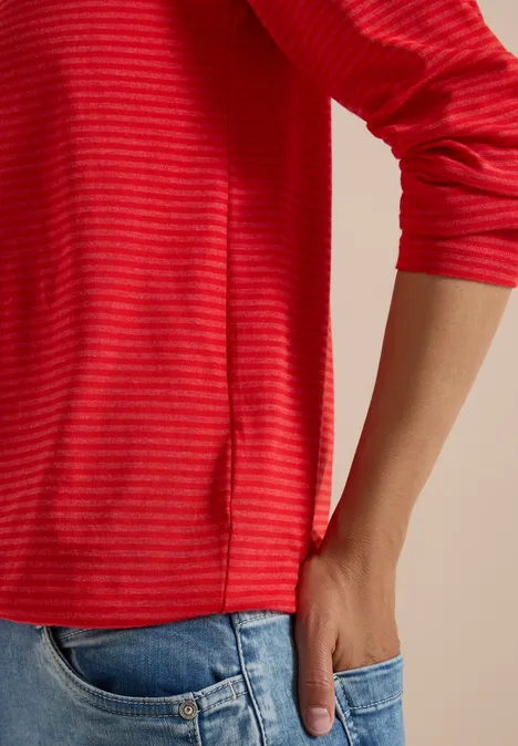 Rotes gestreiftes Langarmshirt, Hand steckt in Jeans-Tasche.