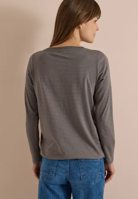 Langarm Shirt mit Boat Neck und Streifen storm grey Frau von hinten, trägt graues gestreiftes Langarmshirt und blaue Jeans vor beiger Wand.