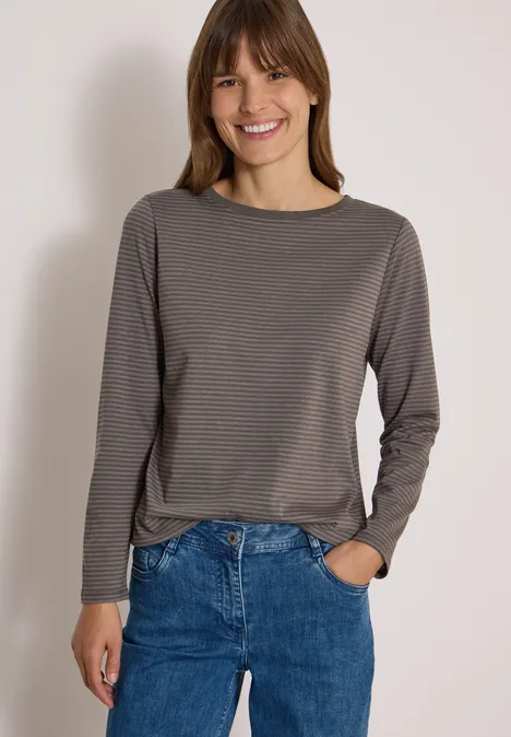 Langarm Shirt mit Boat Neck und Streifen storm grey Eine lächelnde Frau trägt ein grau gestreiftes Longsleeve und blaue Jeans vor hellem Hintergrund.