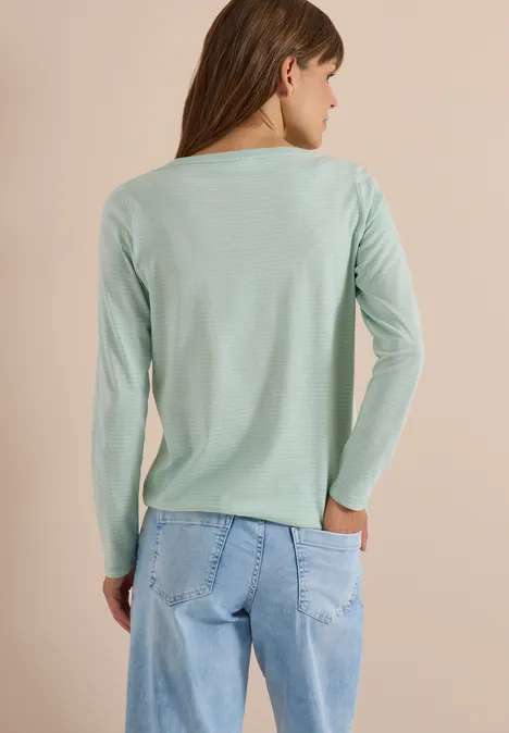Frau von hinten in mintgrünem Langarmshirt und hellblauen Jeans