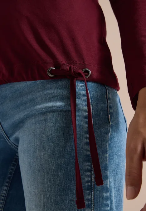 Shirt mit Split Neck im Tunika-Look red wine Person trägt blaue Jeans und ein dunkelrotes Langarmshirt mit Tunnelzug am Saum, Hand seitlich sichtbar.