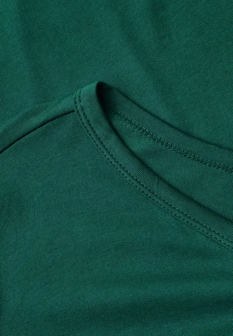 Nahaufnahme eines grünen T-Shirt-Ausschnitts mit sichtbarer Naht