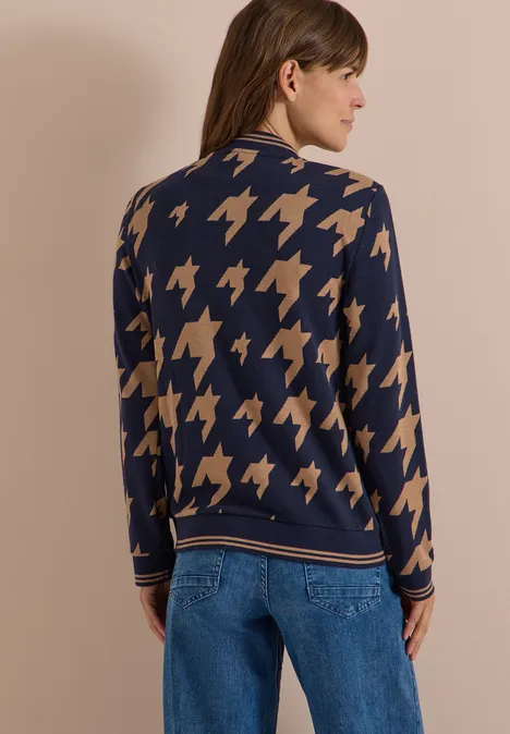 Frau von hinten in navy blauem Pullover mit beigem Hahnentrittmuster und blauer Jeans.