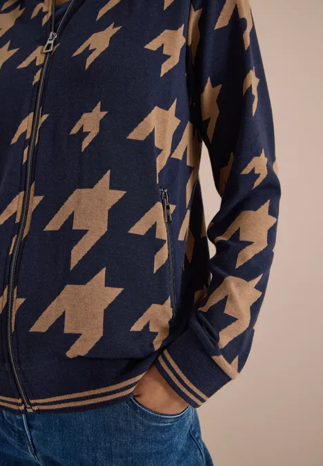 Dunkelblaue Strickjacke mit Reißverschluss, beigem Hahnentrittmuster, seitlichen Taschen und gestreiften Bündchen, zu Jeans.