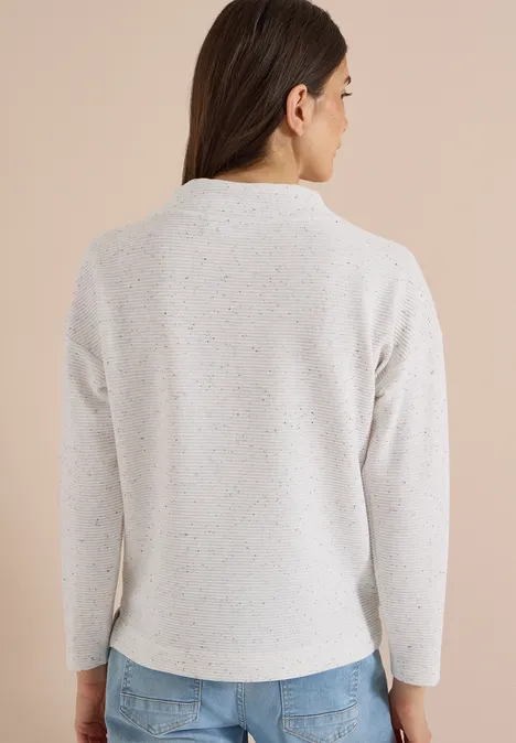 Rückenansicht einer Frau im hellen, melierten Pullover mit langen braunen Haaren.