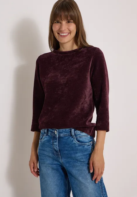T-shirt à manches 3/4 en velours côtelé avec encolure bateau berry red Femme souriante portant un haut en velours violet et un jean bleu.