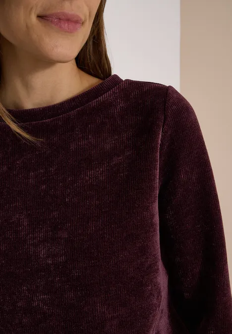 T-shirt à manches 3/4 en velours côtelé avec encolure bateau berry red Gros plan d'une personne portant un haut en velours bordeaux sur fond clair divisé.