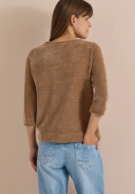 T-shirt à manches 3/4 en velours côtelé avec encolure bateau creamy mocha Femme de dos en pull marron et jean bleu clair, positionnée de profil vers la droite, sur un fond neutre.