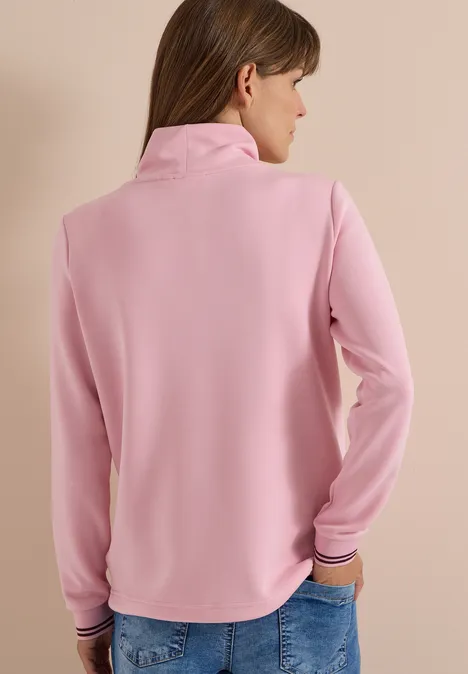 Rückansicht einer Frau in rosa Pullover mit Stehkragen.