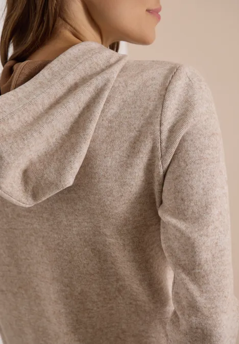 Vue arrière d’une personne portant un sweat à capuche beige chiné en maille douce et confortable.