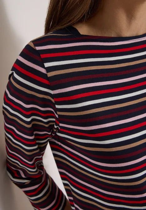 Brustbereich einer Person mit langärmligem Shirt in bunten, horizontalen Streifen.