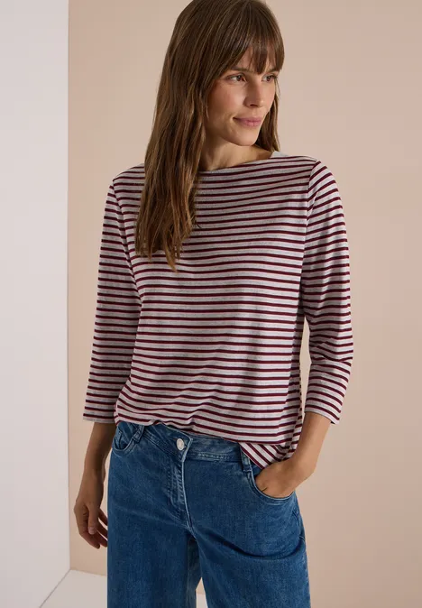 3/4-Arm Shirt mit Boat Neck und Streifen light grey melange Frau mit braunem Haar in gestreiftem Langarmshirt und blauen Jeans vor neutralem Hintergrund.