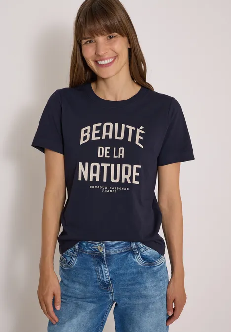 Lächelnde Frau im navyblauen T-Shirt mit Schriftzug ‚Beauté de la Nature‘.